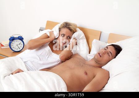Eine blonde Frau bedeckt ihre Ohren, weil ihr Mann schnarcht, 30, 35, Jahre alt, blond, blond, Studioaufnahme, Bundesrepublik Deutschland Stockfoto