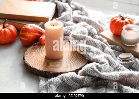Holztablett, brennende Kerze und Kürbis auf weißem Grunge-Fensterbrett im Zimmer, Nahaufnahme Stockfoto