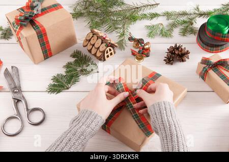 Hände binden ein Band an eine braune Geschenkbox Stockfoto