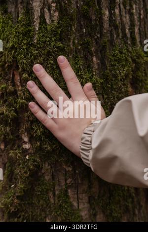 Kind Hand berührt Baumrinde im Wald – Verbindung mit Natur, Achtsamkeit, sensorisches Lernkonzept und Umweltbewusstsein Stockfoto