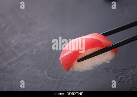 Sushi-Kollektion auf dunkler Oberfläche, die Sie mit Essstäbchen genießen können Stockfoto