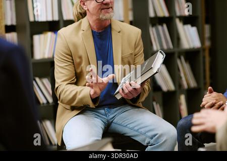 Kaukasier mittleren Alters, der Buch in der Bibliothek präsentiert Stockfoto