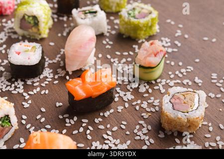 Sushi-Mosaik mit verschiedenen Arten von Sushi auf einem Holztisch mit Streureis Stockfoto