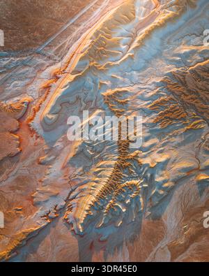 Die von der Sonne geküsste Erde aus der Luft zeigt einen Wandteppich aus goldenen Canyons und blassblauen Sedimenten, geätzt von Zeit und Elementen, Kyzylkum, Mangystau Reg Stockfoto