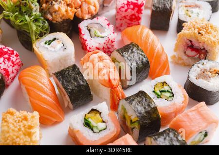 Sushi-Collage mit verschiedenen Typen, die auf einer weißen Oberfläche angeordnet sind, für eine attraktive Anzeige und Probenahme Stockfoto