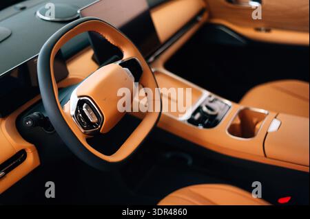 Hochwertiger Innenraum mit gesteppten, braunen Ledersitzen, perforierten Belüftungszonen und schwarzer Konsolenarmlehne Stockfoto