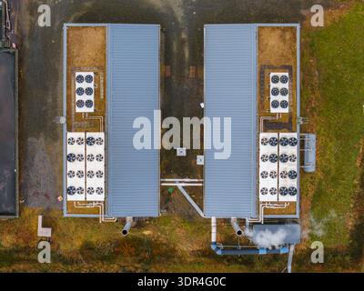 Luftansicht auf Industriegebäude mit grünen Dächern und silbernen Spitzen, die Rauch in den Himmel pusten, Trédarzec, Bretagne, Frankreich. Stockfoto