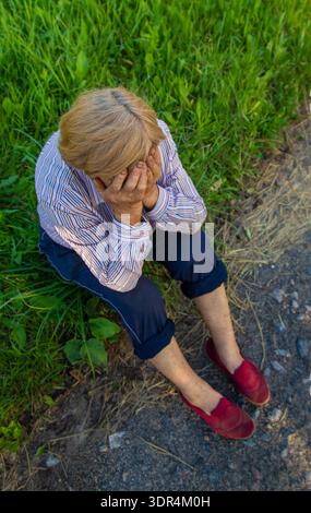 Die alte Frau fühlt sich auf der Straße schlecht, Kopfschmerzen. Selektiver Fokus. Stockfoto