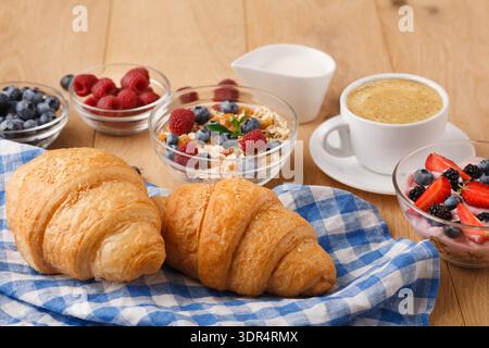 Croissants, Obst, Joghurt und Kaffee auf einem Tisch für ein Frühstückstreffen mit Freunden Stockfoto
