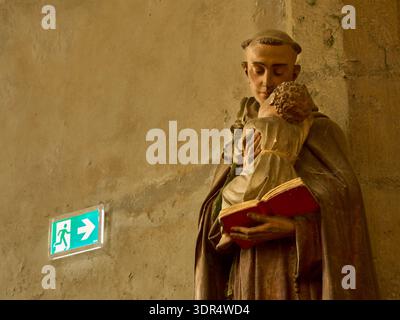 Modernes grünes Ausstiegsschild neben einer mittelalterlichen Steinstatue in der Kirche Saint-Pierre, Chartres, Frankreich Stockfoto