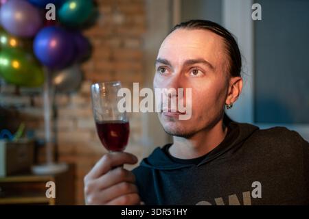 Applaus. Porträt eines fröhlichen, fröhlichen jungen bärtigen Mannes, der Glas hält, Rotwein trinkt, Toast und Selfie spricht, Videoanrufe macht, Hand t erreicht Stockfoto