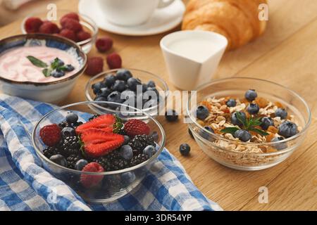 Sammlung von Frühstücksartikeln mit Beeren, Joghurt und Müsli auf einem Holztisch Stockfoto