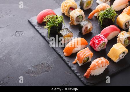 Sushi-Kollektion auf einem Schieferbrett mit verschiedenen Arten von Sushi-Rolls und Aromen Stockfoto