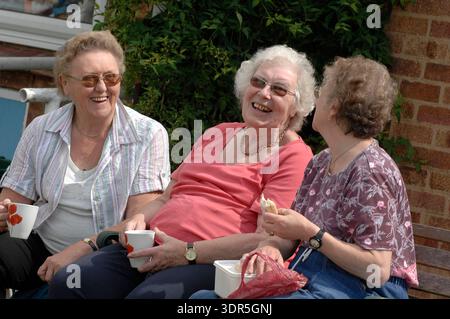 Ältere Bewohner eines britischen Pflegeheims, die sich in einem Gemeinschaftsraum verständigen und miteinander interagieren. Diese Gruppenaktivitäten sind strukturiert, um die Kommunikation zu fördern und emotionale Unterstützung unter Kollegen zu bieten. Regelmäßiges soziales Engagement ist für die Erhaltung der kognitiven Gesundheit, die Verringerung der Isolation und die Verbesserung der allgemeinen Lebensqualität älterer Erwachsener in einer häuslichen Pflegeumgebung von entscheidender Bedeutung. Stockfoto