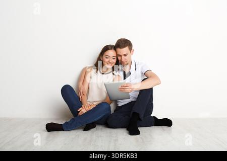 Verbringen Sie Zeit miteinander, während Sie ein Tablet auf dem Boden in einem einfachen Raum verwenden Stockfoto