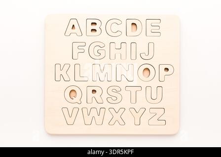Puzzle aus Holz mit ausgeschnittenen Buchstaben auf glattem Hintergrund für Lernspiele Stockfoto
