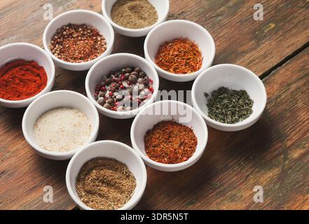 Sammlung verschiedener Gewürze in kleinen Schüsseln auf Holztisch angeordnet Stockfoto