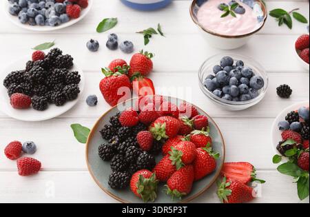 Frische Beeren auf einem Tisch mit Joghurtschalen in einer Kollektion Stockfoto