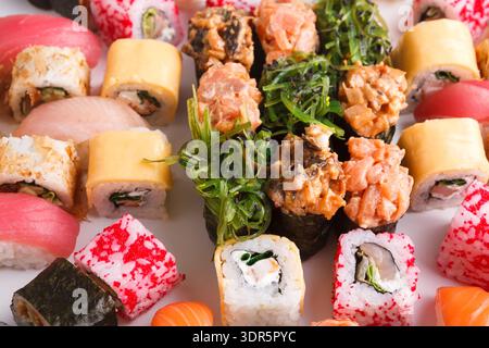 Sushi-Collage mit verschiedenen Rollen und Sushi-Typen auf einer weißen Platte Stockfoto