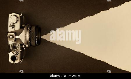 Retro-Fotokamera auf Sepia-getöntem strukturiertem Papierhintergrund mit Kopierraum Stockfoto