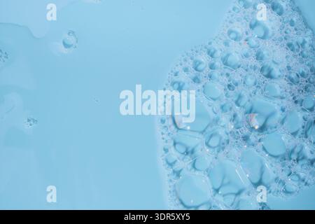 Blaue Flüssigkeit mit transparenter Seifenschaumstruktur und abstrakten Blasen Stockfoto