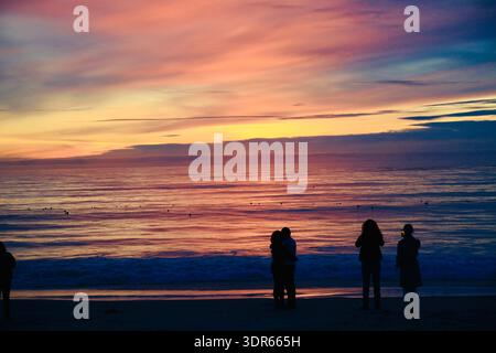 Die Silhouette von vier Personen, die bei Sonnenuntergang am Strand stehen, die Aussicht betrachten und Fotos machen Carmel-by-the-Sea, Monterey Peninsula, Kalifornien, USA Stockfoto