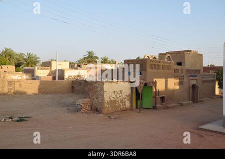 Blick aus einem hohen Winkel auf traditionelle mehrstöckige Lehmziegelhäuser und Ruinen neben einem üppigen Dattelpalmenhain in Al Qasr, Dakhla Oase, Ägypten Stockfoto