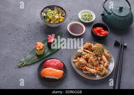 Köstliche Auswahl asiatischer Gerichte auf einem Tisch mit Stäbchen und Tee Stockfoto