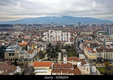 Panoramablick auf Sofia, Bulgarien, mit dichten roten Dächern und städtischen Straßen, die sich zum schneebedeckten Vitosha-Berg unter bedecktem Himmel erstrecken Stockfoto