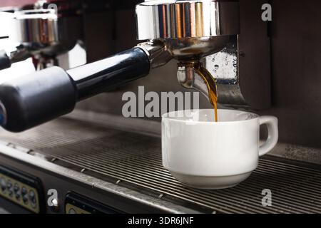 Kaffeezubereitungsprozess in einem Café mit Espressomaschine mit darunter liegendem Becher Stockfoto