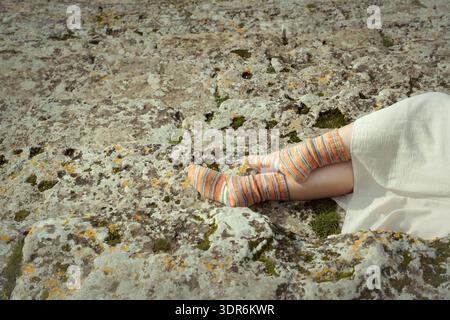Close up photo of a young woman's feet in handmade wool socks resting on the ancient steps of Hierapolis amphitheater. Stockfoto