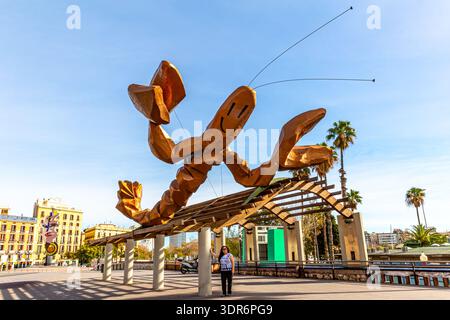 Passeig del Colom mit einer Touristenfrau, die vor der Skulptur La Gambrinus in Port Vell steht, Skulptur des riesigen Hummer mit lächelndem Gesicht, Buildi Stockfoto