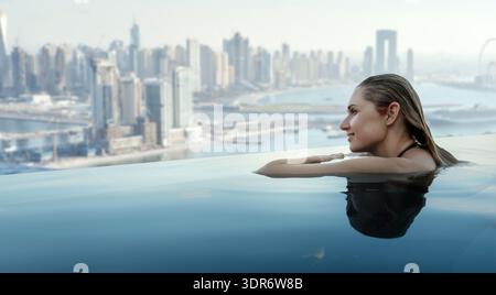 Frau genießt das Panorama von Dubai vom Infinity-Pool auf dem Dach. Kopierbereich Stockfoto