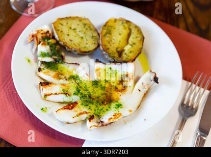 Gegrillter Tintenfisch serviert mit Knoblauch und Petersilie Stockfoto