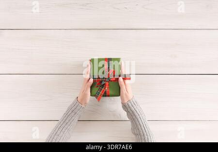 Geschenkbox mit Händen auf Holztisch in einem einfachen Setup für Feiern oder Anlässe Stockfoto
