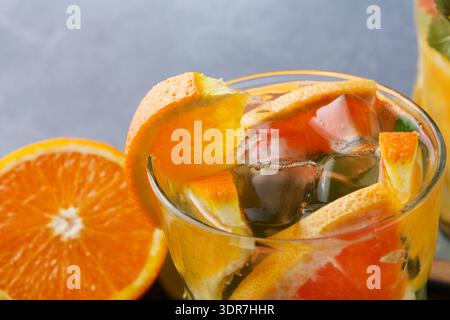 Frisches Fruchtgetränk mit Orange und anderen Zitrusfrüchten in einem klaren Glas auf einem Holztisch Stockfoto