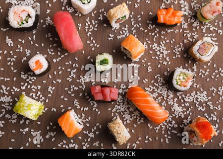 Sushi-Sammlung auf Holztisch mit verstreutem Reis Stockfoto