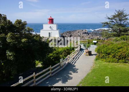 Der Leuchtturm von Amphitrite Point steht an der rauen Küste von Ucluelet, Vancouver Island, mit einem malerischen holzgeländerten Weg, der zum Meer führt. Stockfoto