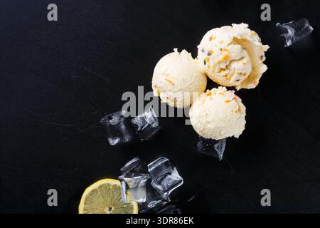 Zitroneneis serviert mit Eiswürfeln und Zitronenscheibe auf schwarzer Oberfläche Stockfoto