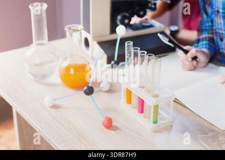 Chemieexperiment an einem Tisch mit mehreren Glaswaren und einem Mikroskop Stockfoto