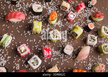 Sushi Collage zeigt verschiedene Arten von Sushi, die auf einer Holzfläche mit Reis angeordnet sind Stockfoto
