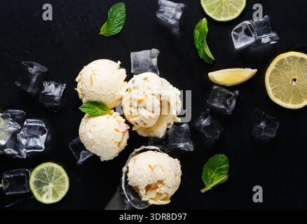 Frisches Zitroneneis serviert mit Minzblättern und Eis auf schwarzem Hintergrund Stockfoto