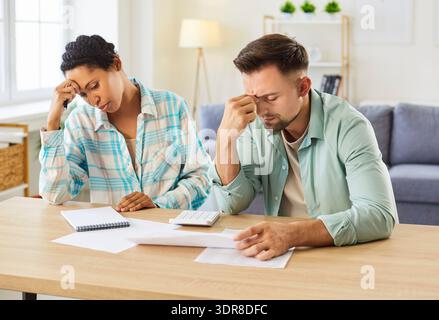 Frustriertes junges Paar, das mit Finanzdokumenten am Tisch sitzt und das Familienbudget plant. Stockfoto