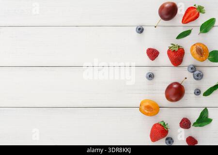 Fruit Collage auf weißem Holztisch mit verschiedenen Beeren und Steinfrüchten Stockfoto