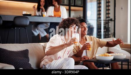 Männer, Freunde und begeistert vom fernsehen auf dem Sofa mit Sportspielen, Turnieren oder Match im Wohnzimmer. Leute, glücklich und trinken auf der Couch Stockfoto