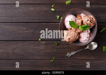 Schüssel Eiscreme mit drei Geschmacksrichtungen und frischer Minze auf einem Holztisch Stockfoto