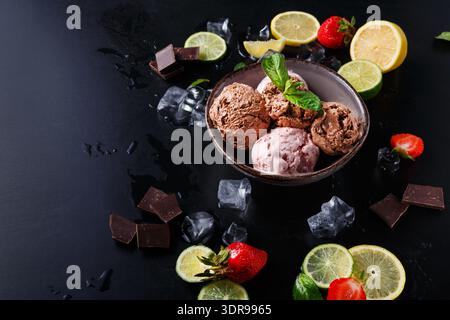 Schokoladen- und Erdbeereis mit frischem Obst und Schokoladenstückchen auf dunklem Hintergrund Stockfoto