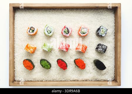 Farbenfrohe Sushi Rolls in einem Holztablett mit Reis in einer sauberen Umgebung Stockfoto