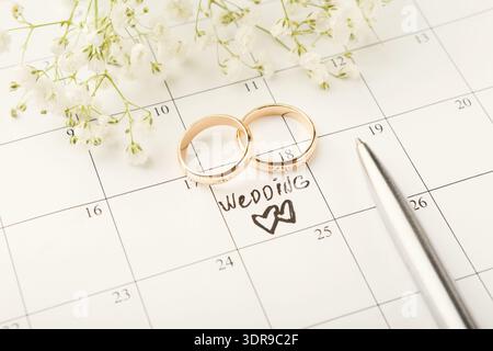 Hochzeitsdatum mit Ringen und Blumen auf einem Kalender für eine besondere Veranstaltung Stockfoto