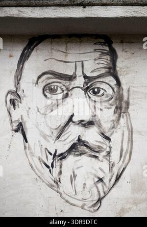Großes handgemaltes schwarz-weißes Street Art Porträt eines bärtigen älteren Mannes mit Rundbrille und einem Spitzbart, der direkt auf einem weißen Stein gemalt ist Stockfoto